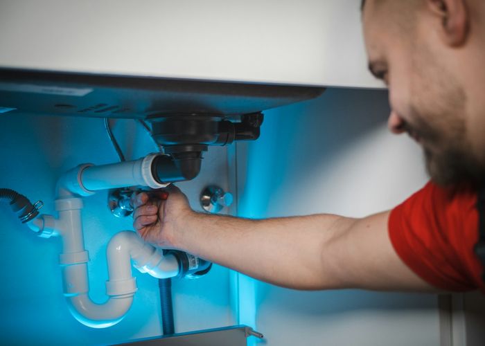 Encanador instalando tubulação sob a pia